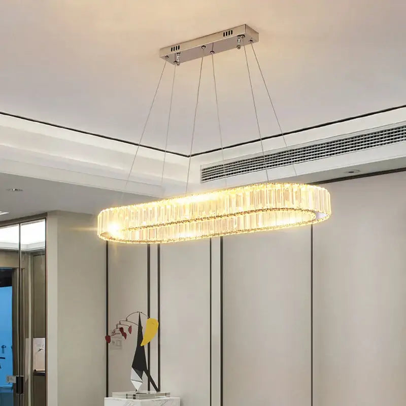 A modern chrome crystal oval led chandelier with hanging rods emitting warm light for luxury living room decorbites crystal oval