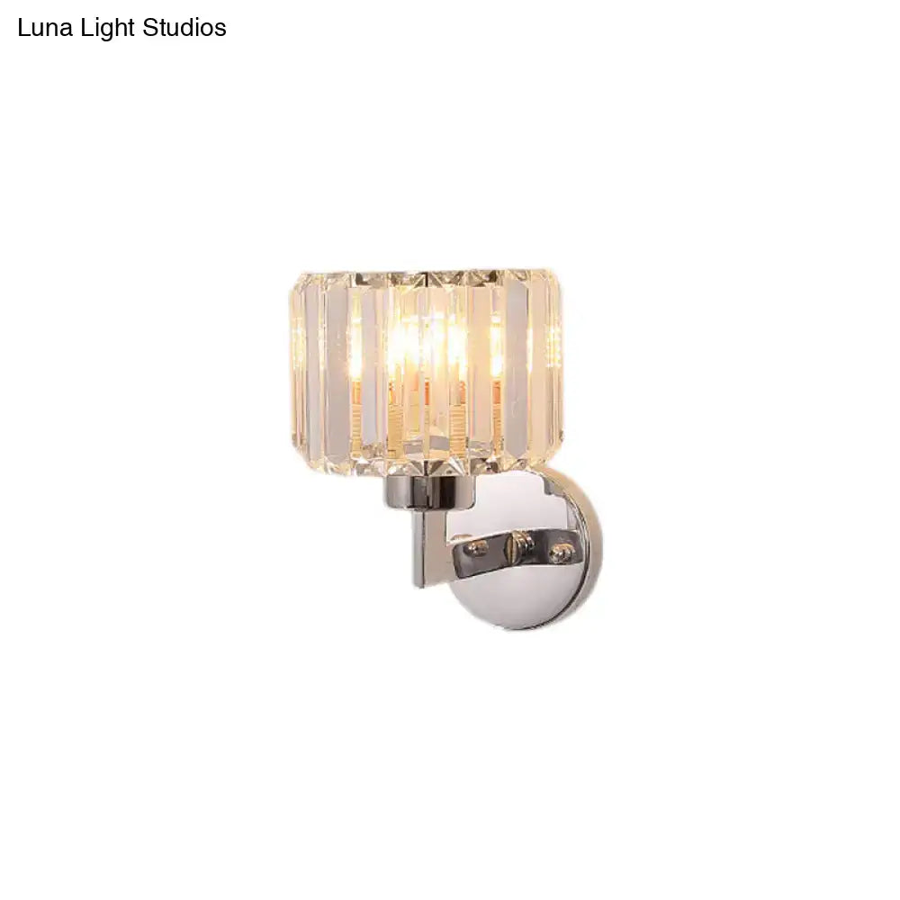 Modern chrome crystal sconce light with cylindrical faceted shade refracting warm light for hallway wall mount