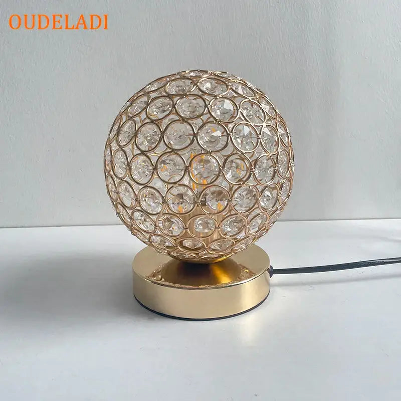 Modern chrome decorbites crystal table lamp with gold-toned ball, faceted clear crystals, and sleek circular base for bedroom