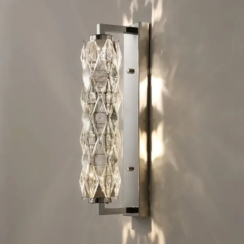 Modern chrome crystal wall lamp with sleek frame and faceted crystal cylinder for luxury bedroom lighting decorbites crystal wall