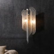 Modern chrome crystal wall sconce with curved frame and clear cascading beads for bedroom bedside lighting