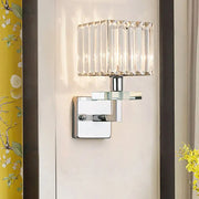Modern chrome cuboid crystal wall mounted light with faceted glass shade and polished metal base for bedroom use