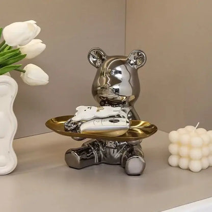 Modern chrome decorbites bear doll made of shiny metallic material holding a golden doll storage tray for key storage