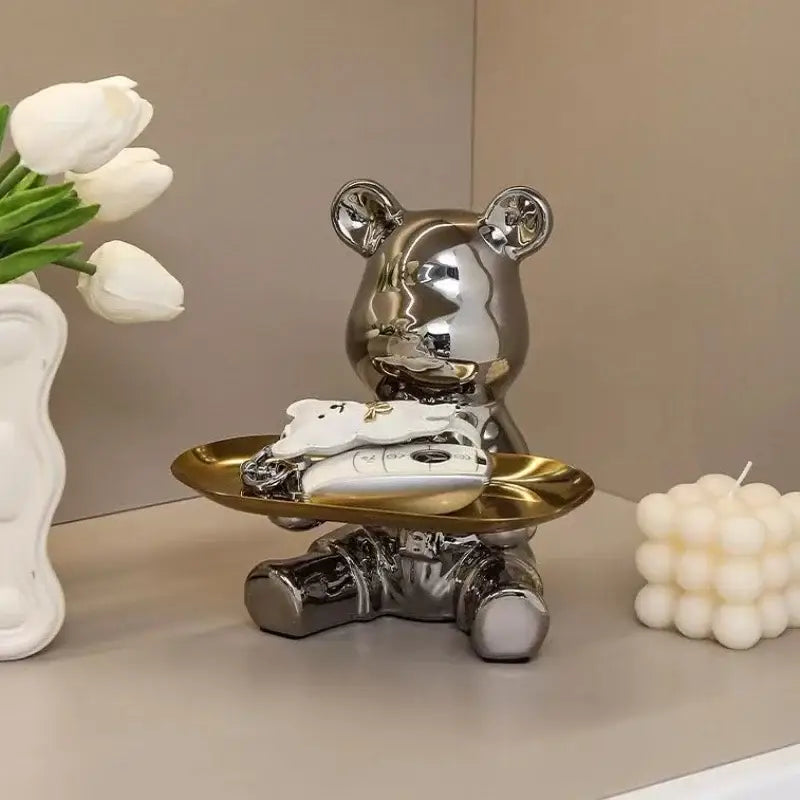 Modern chrome decorbites bear doll made of shiny metallic material holding a golden doll storage tray for key storage