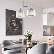 DecorBites modern chrome pendant light with cylindrical crystal shades hanging above dining table island