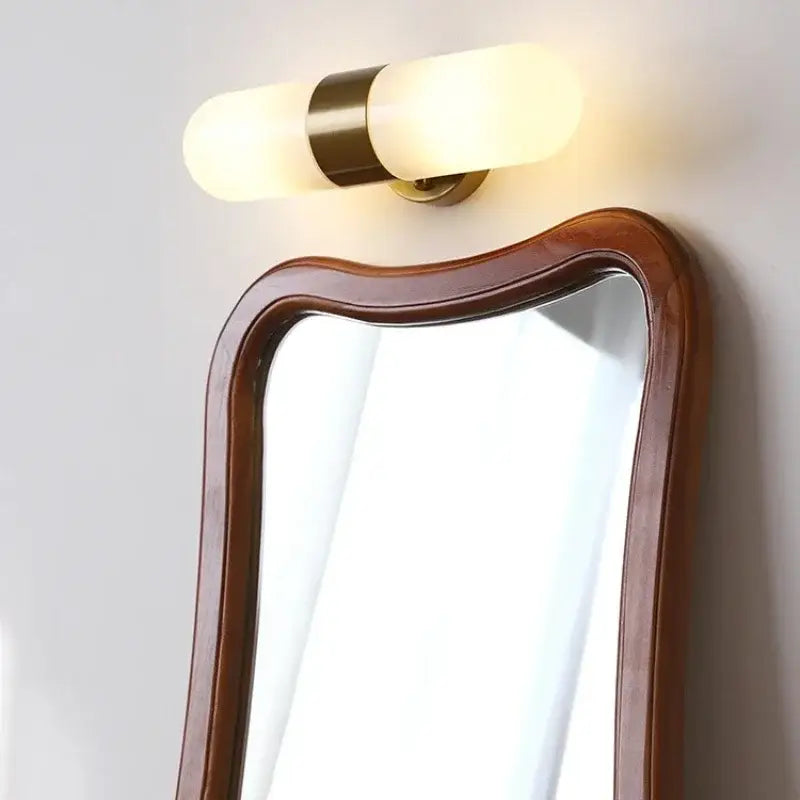Warm-toned cylindrical vanity mirror light with frosted glass shades and brass-finished metal band for bathroom use