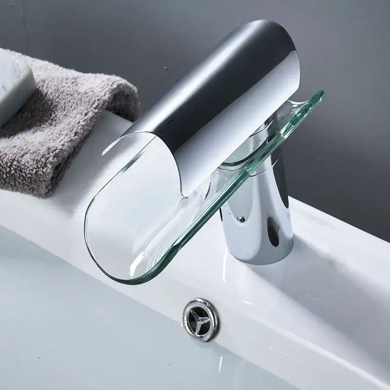 Modern chrome glass spout basin faucet with sleek curved spout and transparent glass accent for bathroom use
