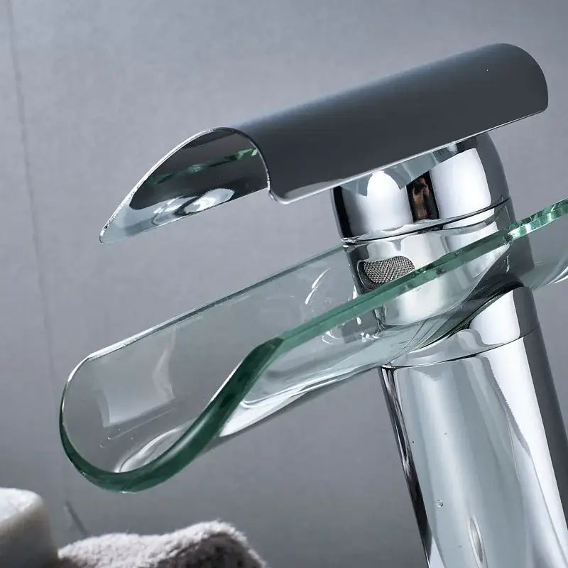 Modern chrome basin faucet with a sleek curved glass spout and handle for bathroom glass spout basin waterfall design