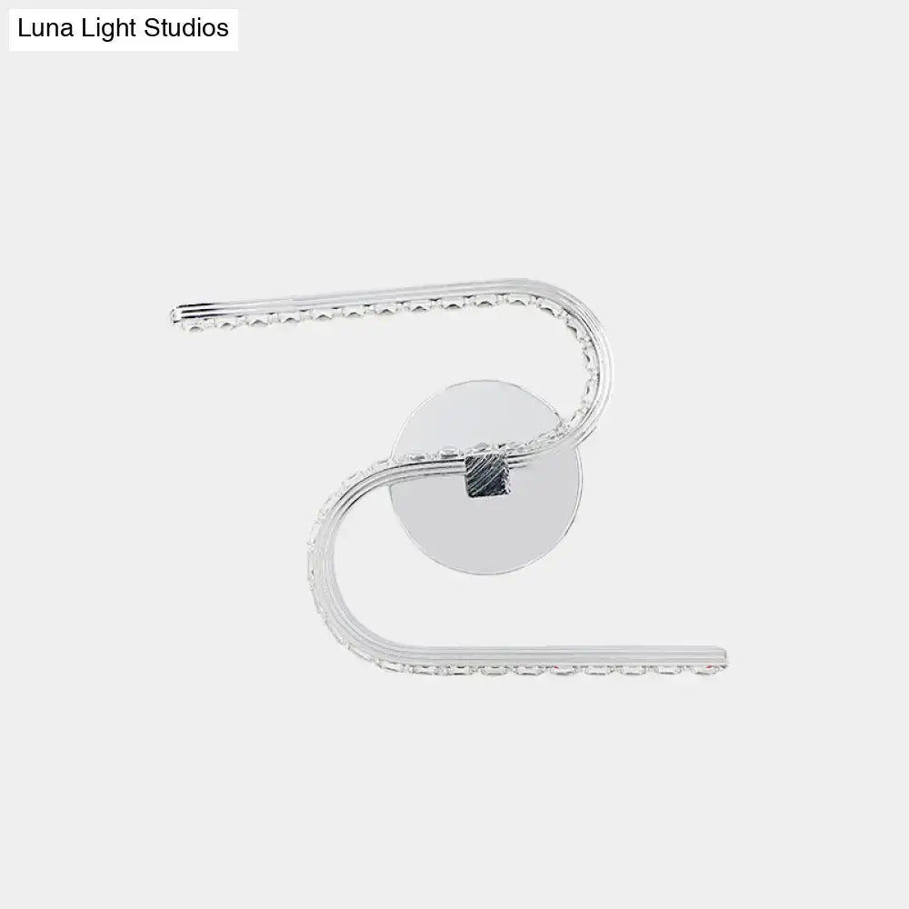 Modern chrome s-shape led wall sconce with silver acrylic shade and embedded crystals emitting warm white light