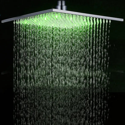 Modern chrome square rainfall shower head with led lights illuminating cascading water streams in bathroom faucet