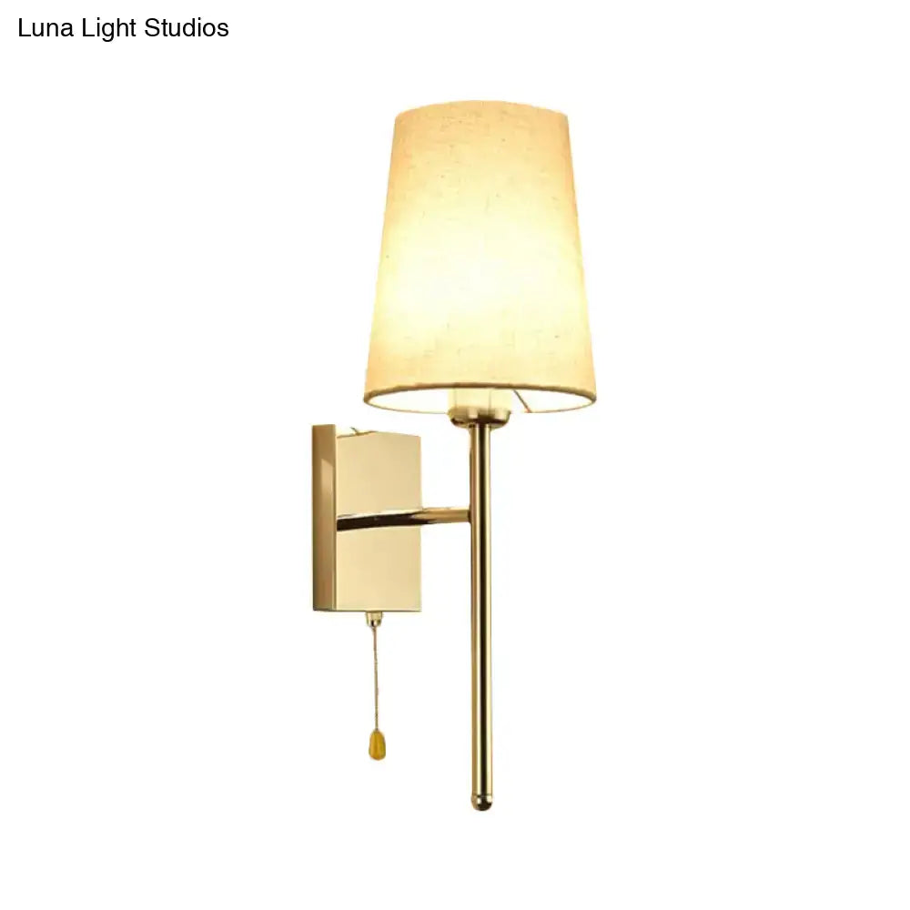 Modern chrome tapered wall sconce with gold finish beige fabric shade and pull chain for bedroom lighting