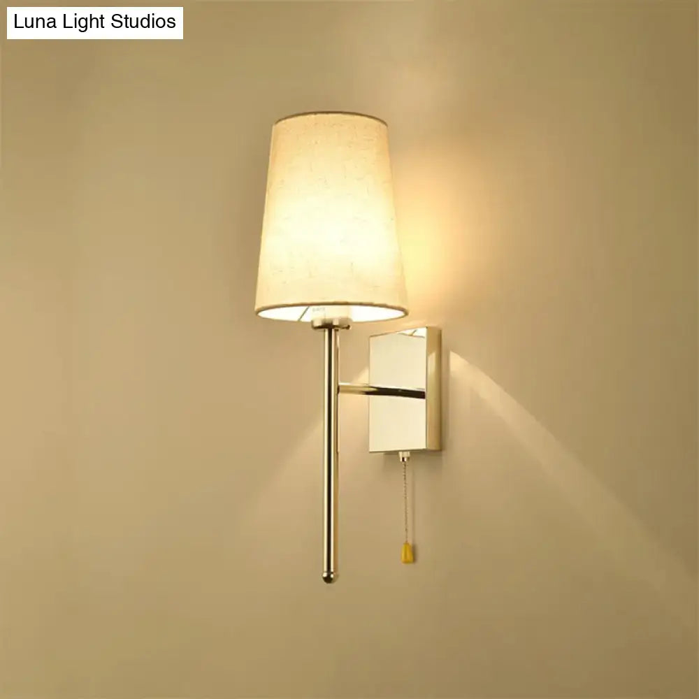 Modern chrome tapered wall sconce with a sleek chrome finish and off-white fabric shade for bedroom lighting