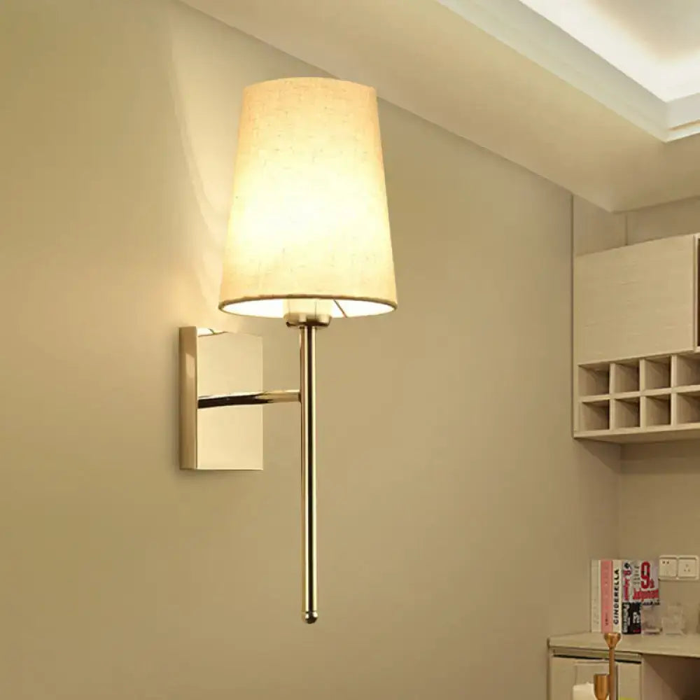 Modern chrome tapered wall sconce with a sleek metallic arm and warm beige fabric shade for bedroom lighting