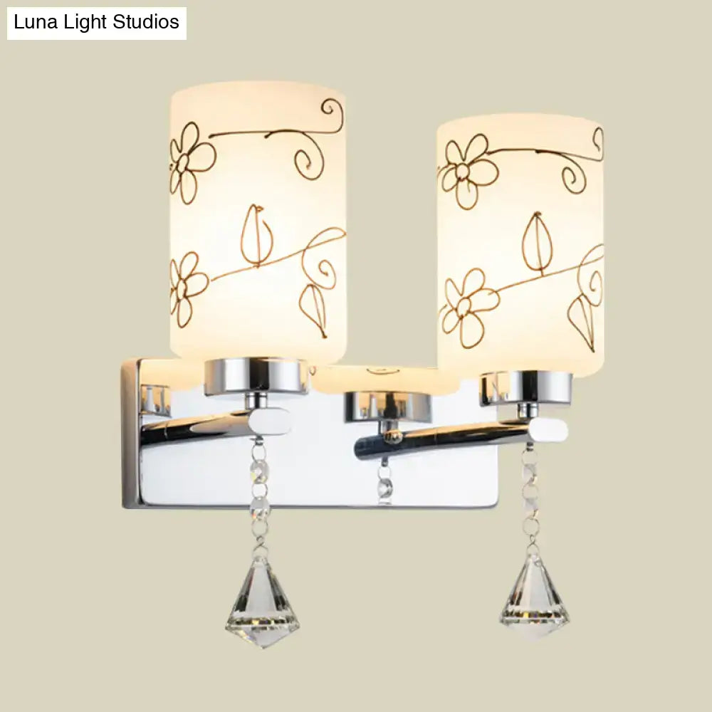 Modern chrome white glass cylinder wall sconce with two frosted white glass shades and crystal pendants for bedroom lighting