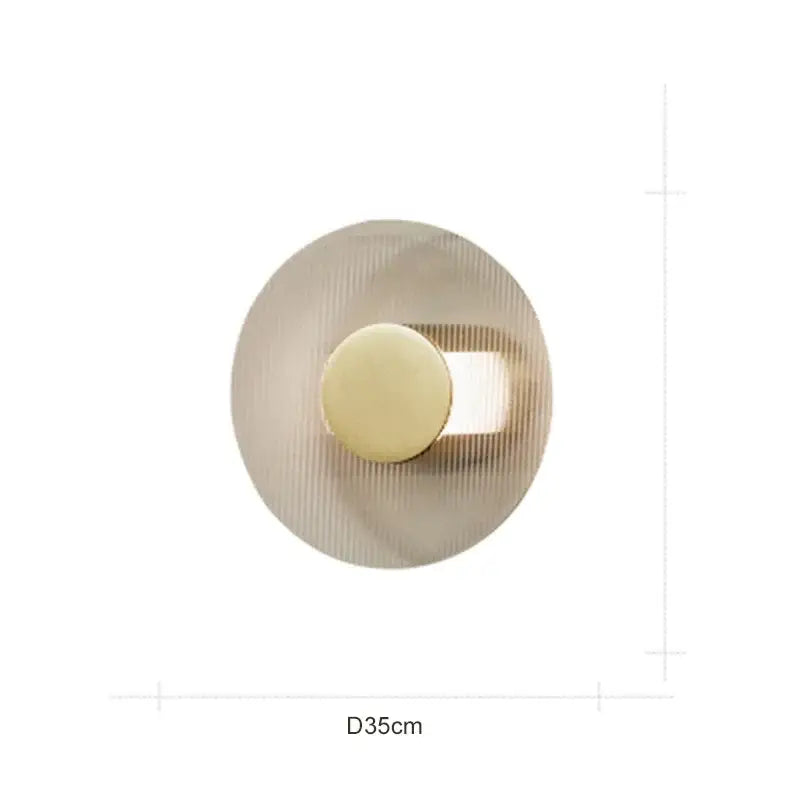 Modern circular brushed gold wall lamp with concentric ridged texture and central light source for elegant glass decorbites wall