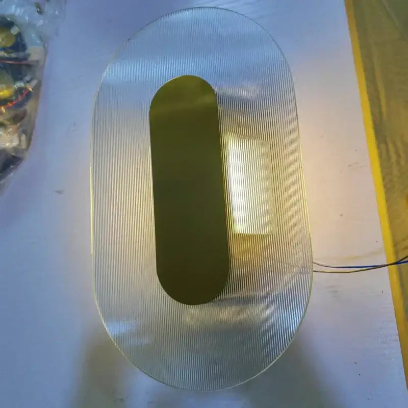 Modern circular brushed metallic wall lamp with a translucent ribbed glass diffuser and gold-toned accent for elegant glass wall decorbites