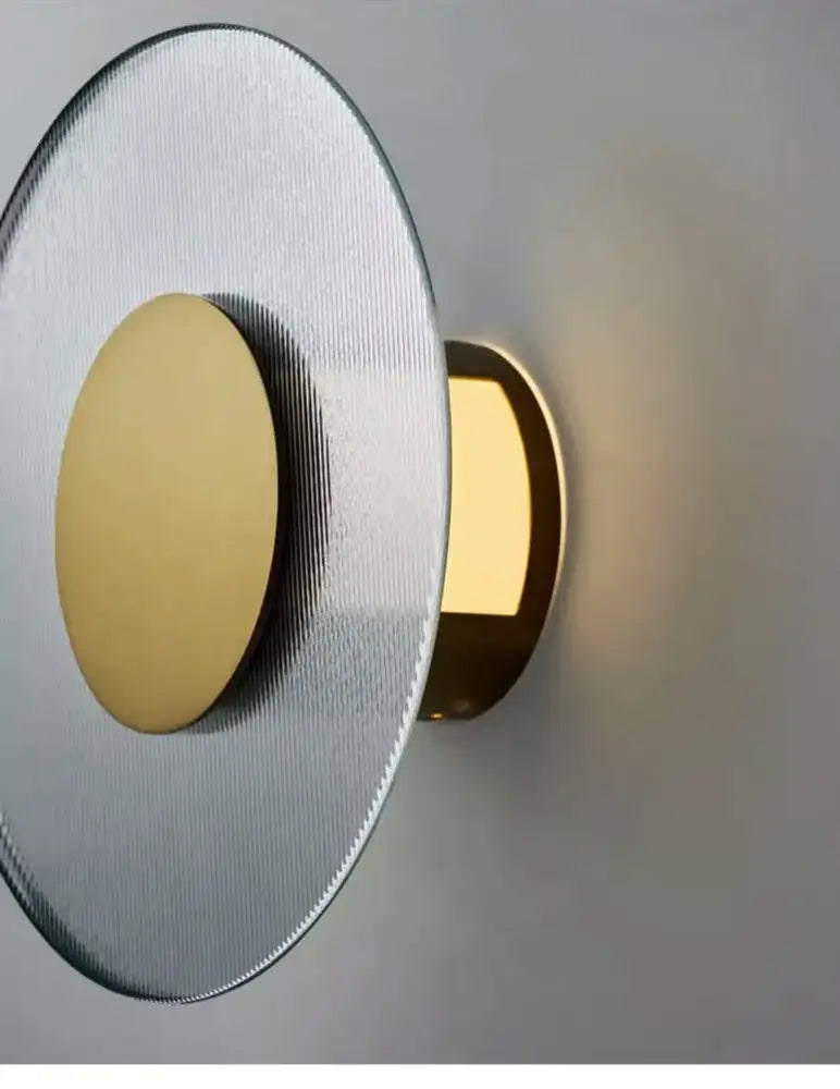 Modern circular brushed metallic wall lamp with a silver face and gold-toned light source for elegant glass wall decorbites decor