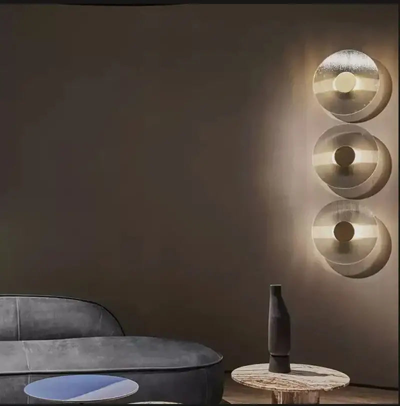 Modern circular brushed metallic wall lamp featuring three warm glowing lights for elegant glass wall decorbites decor