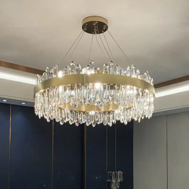 A modern circular gold decorbites crystal chandelier with cascading clear prisms for living room lighting