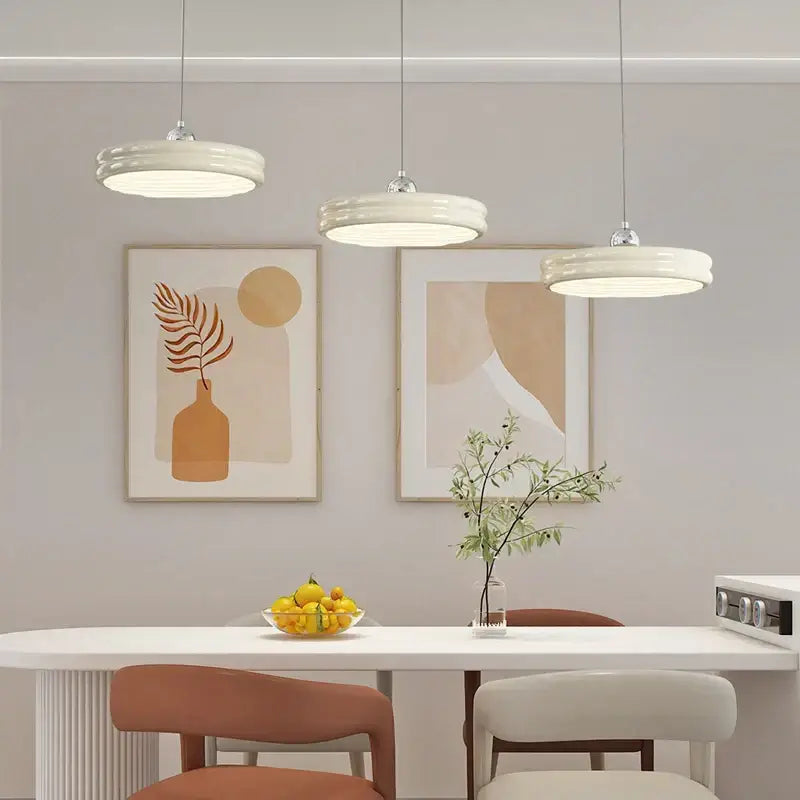Three modern pendant lights with circular pale yellow ceramic shades form a decorbites circular modern chandelier