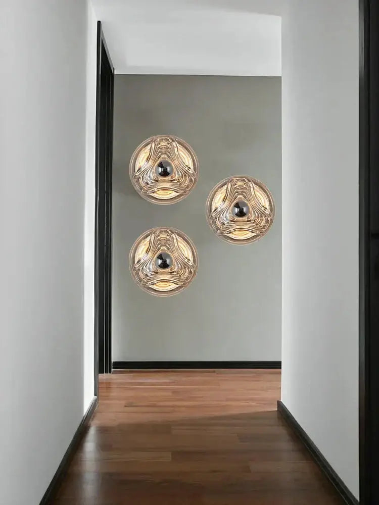 Modern circular swirling designer glass wall lamp with gold accents and black bulbs for bedroom decorbites designer glass