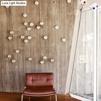 Brown leather chair with metal frame next to modern clear bubble crystal wall light in warm white for living room