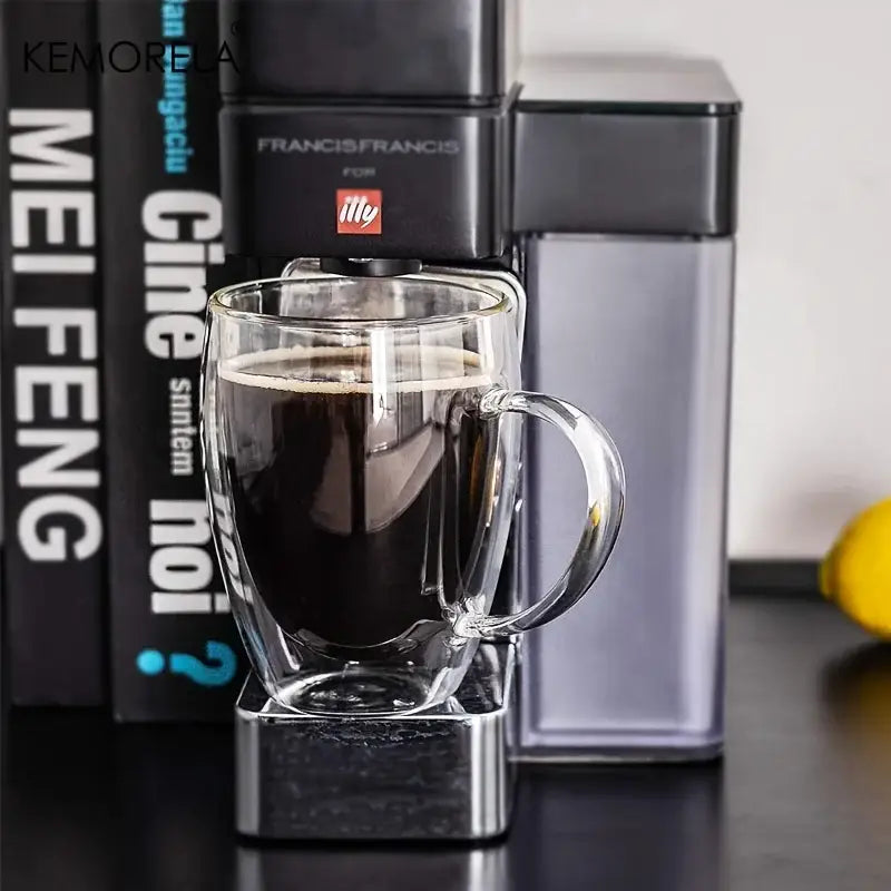 A clear modern double wall glass coffee mug filled with dark espresso featuring a sturdy handle for kitchen use