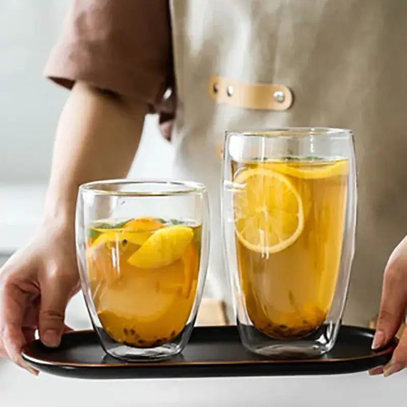 Modern clear double wall glass cup set with lemon slices holding herbal tea in transparent glass tumblers