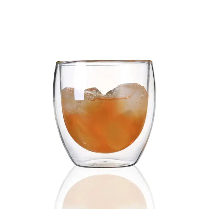 Modern clear double wall glass cup filled with amber liquid and ice cubes for dining room use