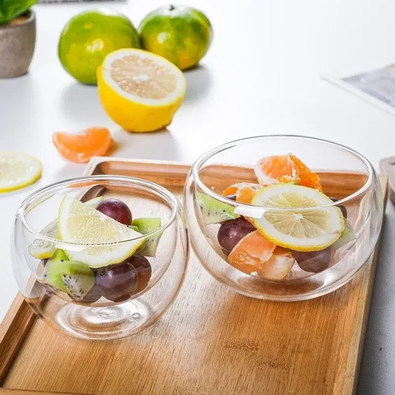 Modern clear double wall glass salad bowl containing colorful fruit slices and grapes for kitchen use