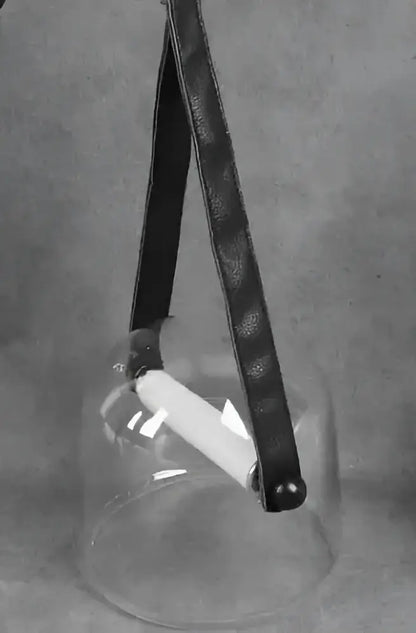Black leather strap hanging from modern clear glass pendant light fixture containing white cylindrical elements