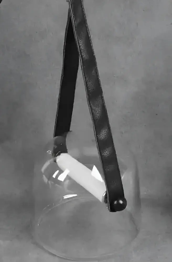Black leather strap hanging from modern clear glass pendant light fixture containing white cylindrical elements