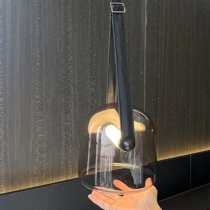 Sleek translucent dark glass bell-shaped pendant light fixture with black leather strap and metal hardware for kitchen