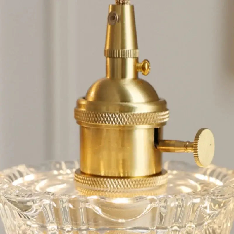 Brass-finished vintage pendant light socket with textured ridged bands and decorative knob in clear glass copper design