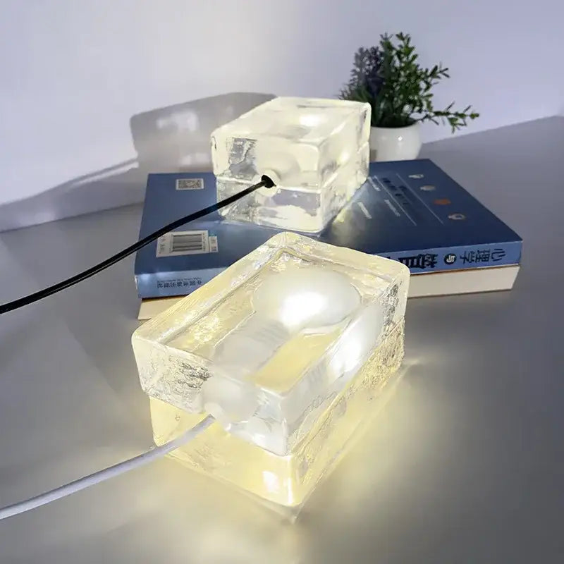 Modern clear glass cube led table lamp with warm yellow glow used as a bedroom nightlight and led table lighting