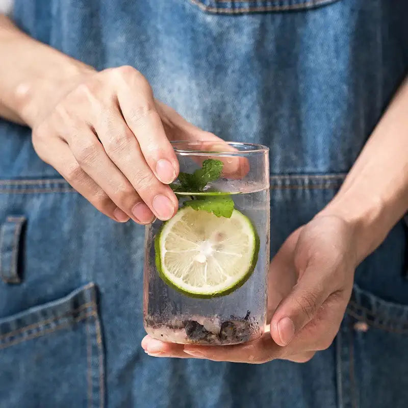 A modern clear glass drinkware cup set featuring a glass tumbler with lime and mint garnishes for refreshing drinks