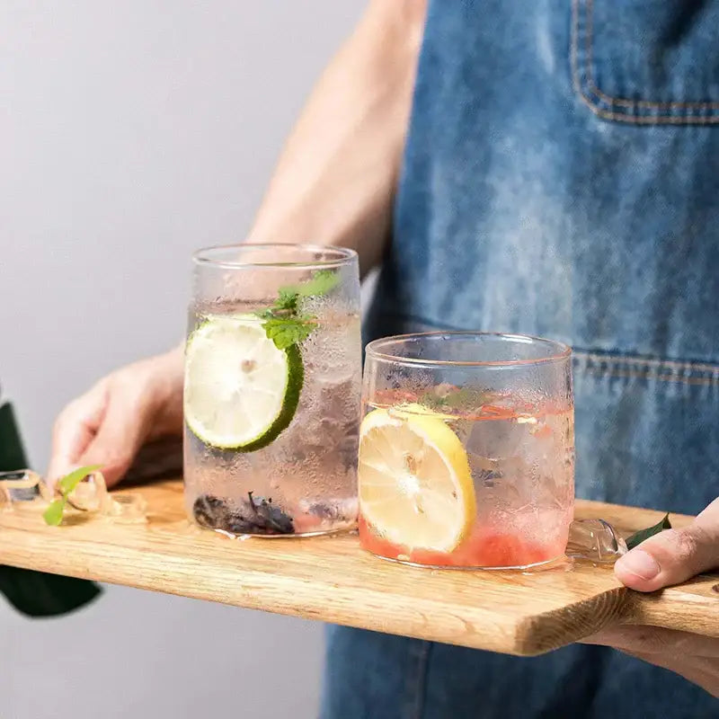 Modern clear glass drinkware cup set featuring two transparent tumblers with garnish for stylish beverage serving