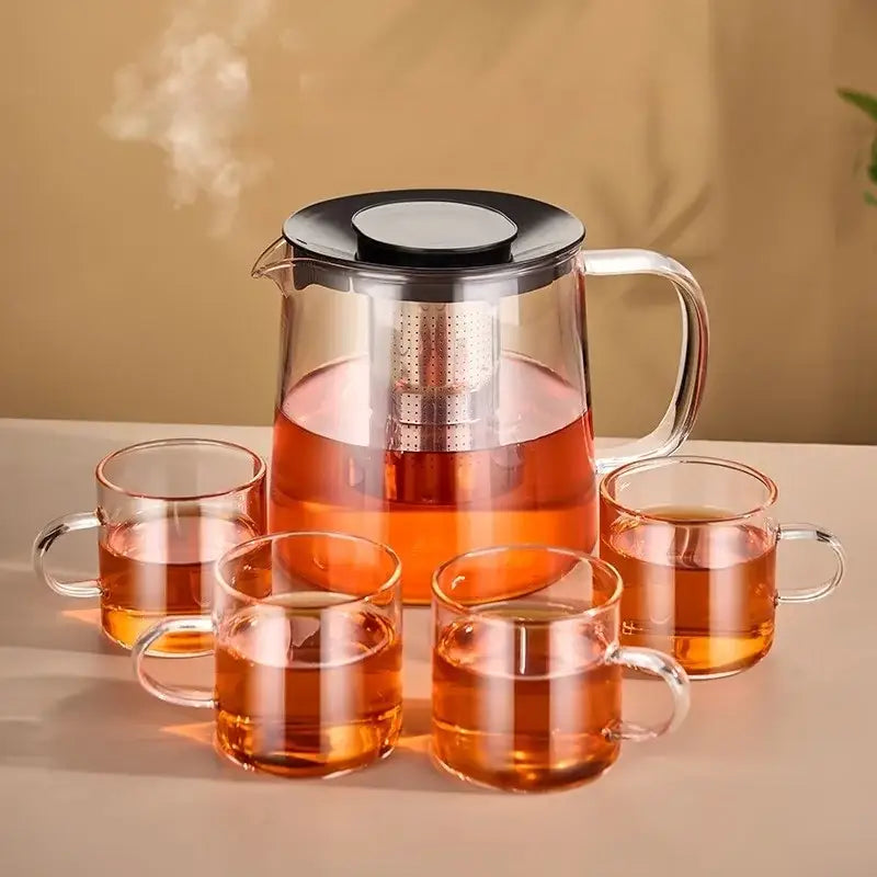 Modern clear glass flower teapot with borosilicate glass infuser and four amber tea filled transparent mugs kitchen tea set