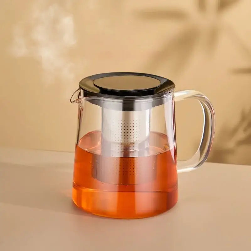 Modern clear glass flower teapot with black lid and stainless steel infuser made of borosilicate glass filled with amber tea