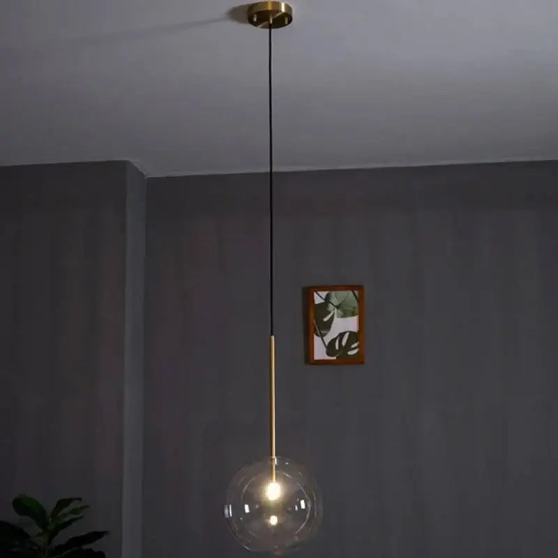 Modern brass pendant light with clear transparent glass globe and black cord for kitchen rod suspension lighting