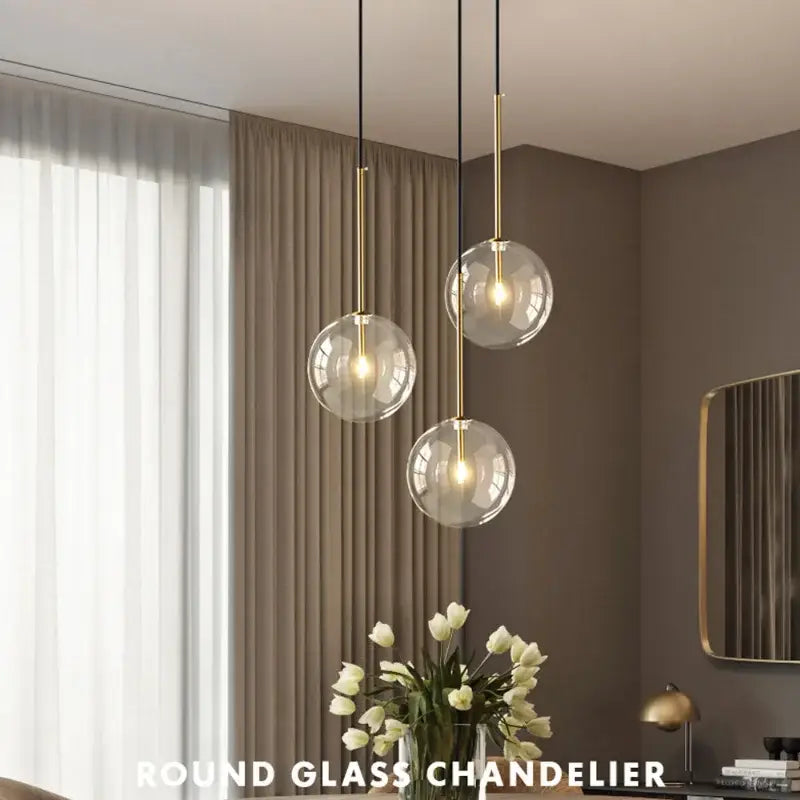 Modern round pendant light with clear glass spherical bulbs and gold-toned metal rods for kitchen suspension