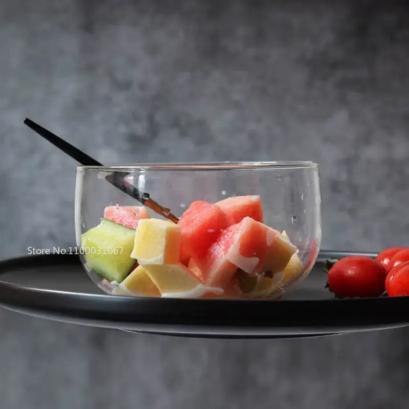 Clear glass salad bowl filled with colorful chopped fruit in a modern glass salad bowl set for kitchen use