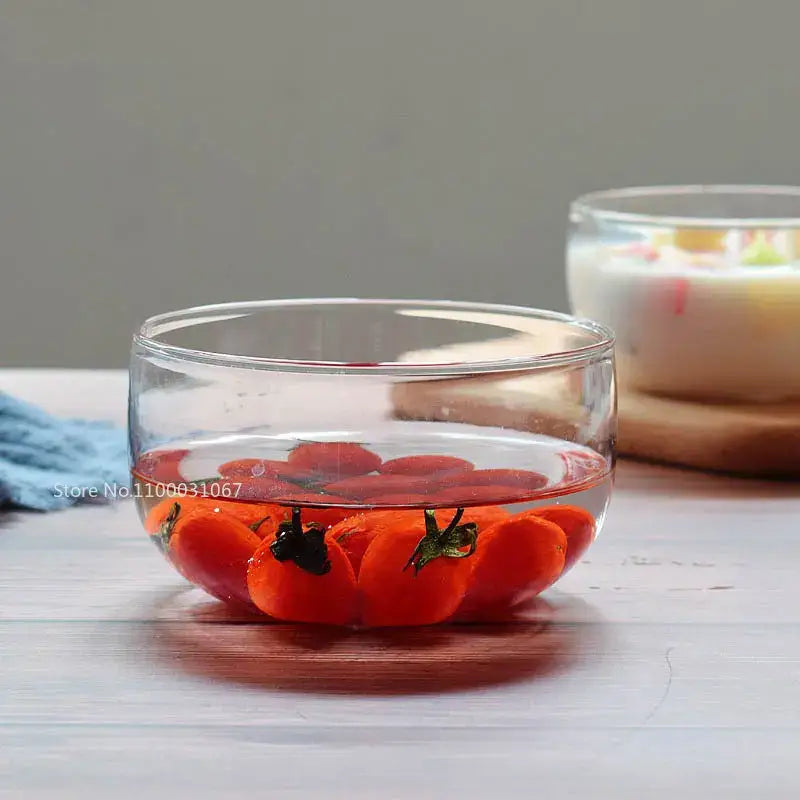 Clear glass salad bowl filled with water and floating red cherry tomatoes from a modern salad bowl set