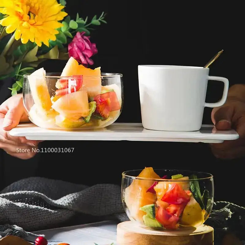 White ceramic tray holding a modern clear glass salad bowl and white mug from a glass salad bowl set