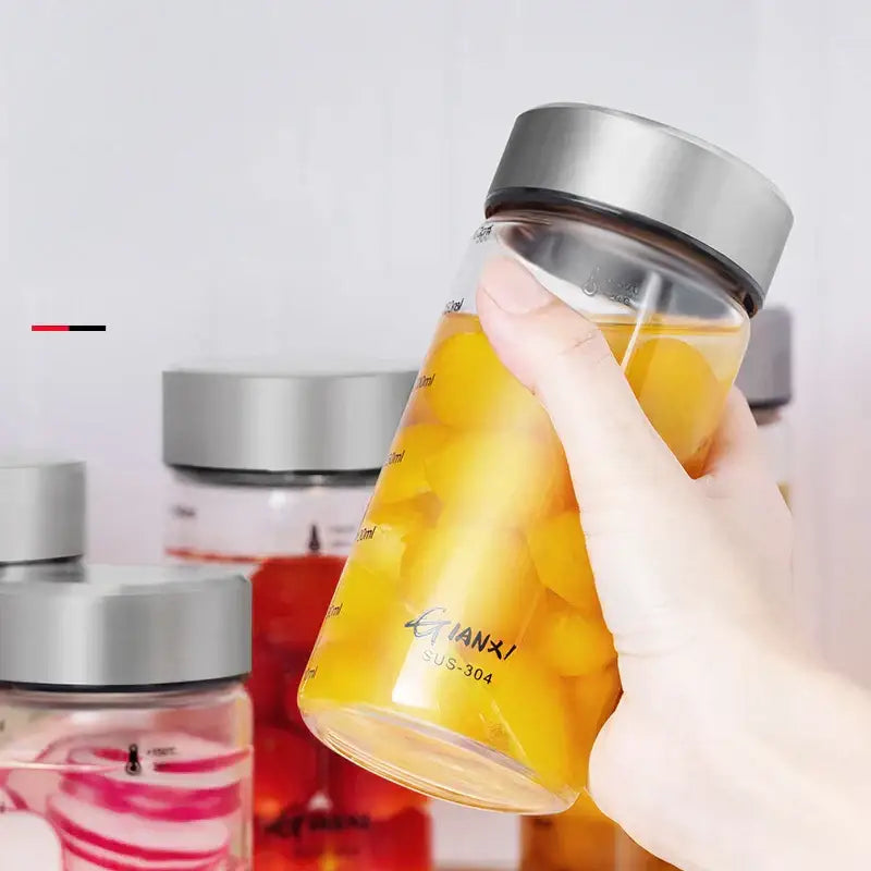 Modern clear glass sealed jug with stainless steel lid filled with yellow fruit pieces for kitchen storage use
