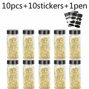 Set of ten modern clear glass seasoning jars with black lids filled with dried herbs for kitchen use