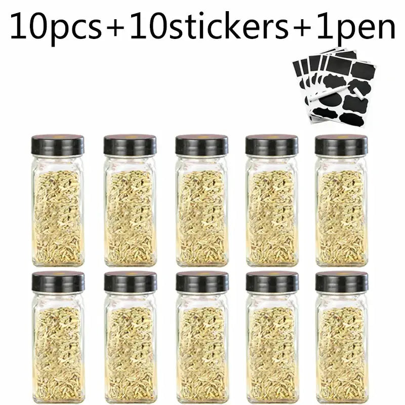 Set of ten modern clear glass seasoning jars with black lids filled with dried herbs for kitchen use