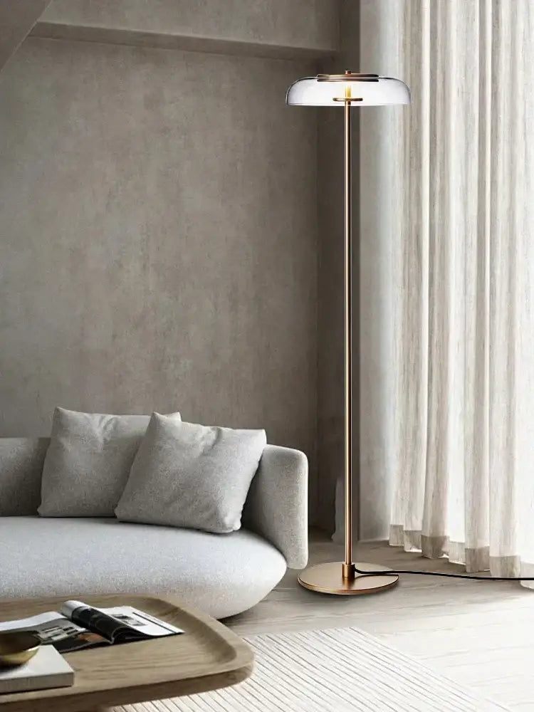 A modern clear glass table lamp with a polished brass finish and translucent white shade for bedroom decorbites