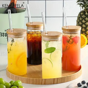 Modern clear glass tumbler cups set of four with bamboo lids and straws filled with colorful iced beverages and fruit garnish