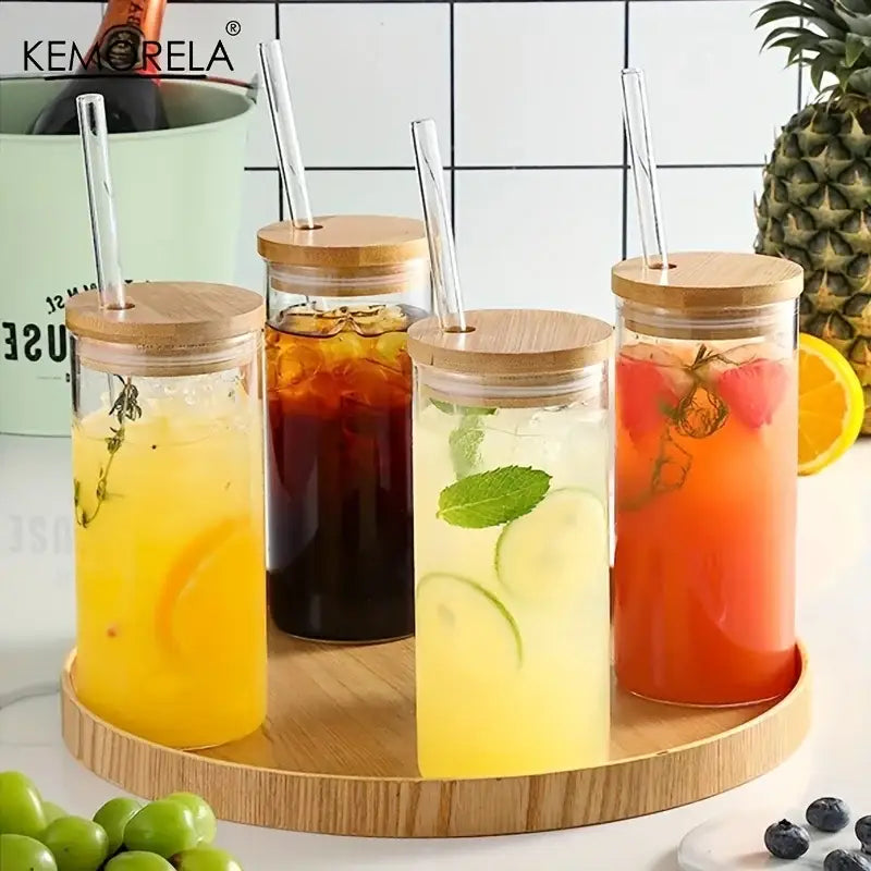 Modern clear glass tumbler cups set of four with bamboo lids and straws filled with colorful iced beverages and fruit garnish